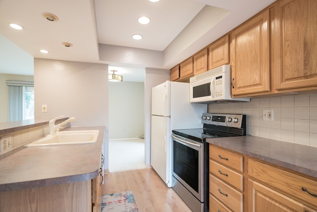 kitchen with a sink, white microwave, decorative backsplash, stainless steel electric range, and light wood-style flooring