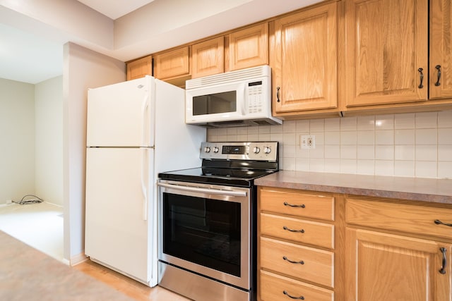 kitchen featuring backsplash, light wood-style floors, light brown cabinetry, and white appliances