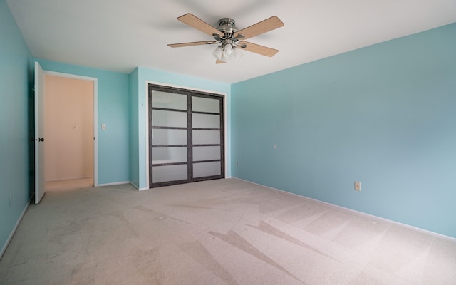 carpeted spare room with a ceiling fan and baseboards