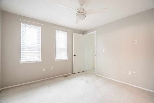empty room featuring visible vents, baseboards, light colored carpet, and ceiling fan