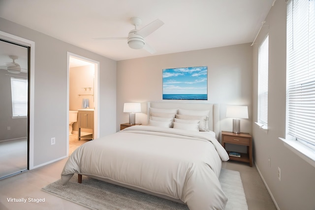 bedroom with a ceiling fan, baseboards, light carpet, and connected bathroom