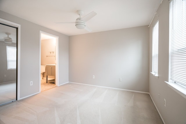 unfurnished bedroom featuring baseboards, ceiling fan, light colored carpet, and multiple windows