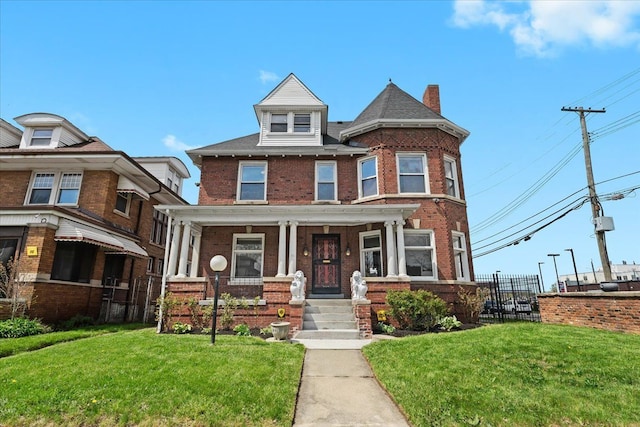 view of front of house with brick siding, covered porch, and a front yard
