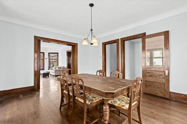 dining space featuring a healthy amount of sunlight, baseboards, an inviting chandelier, and hardwood / wood-style flooring