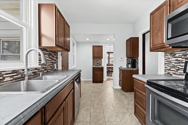 kitchen with backsplash, appliances with stainless steel finishes, dark countertops, a sink, and recessed lighting