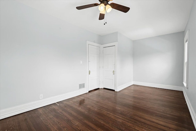 unfurnished bedroom featuring baseboards, a ceiling fan, dark wood-style flooring, and visible vents