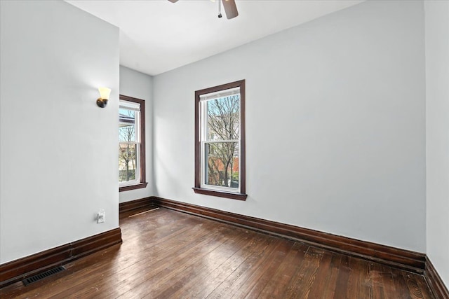 spare room featuring visible vents, a ceiling fan, plenty of natural light, and hardwood / wood-style flooring