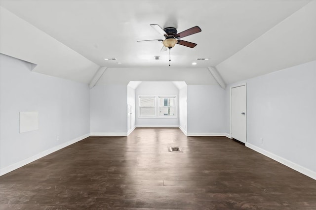 additional living space with visible vents, a ceiling fan, baseboards, vaulted ceiling, and dark wood-style floors