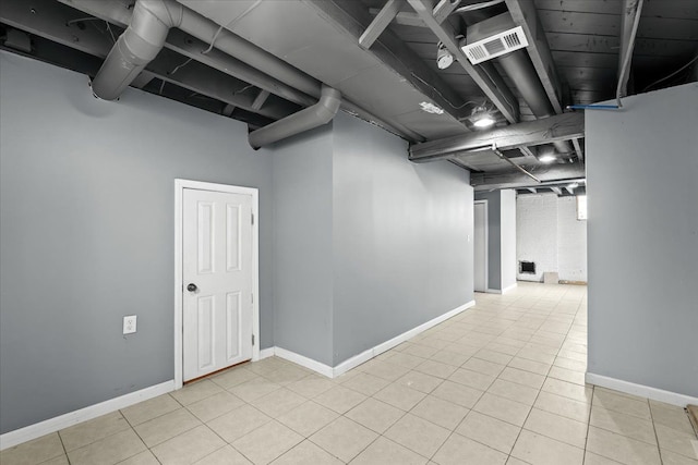 finished basement with baseboards, light tile patterned flooring, and visible vents