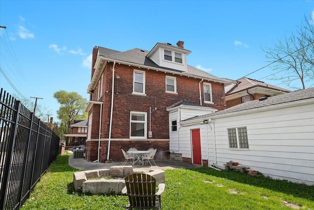rear view of property with fence, a chimney, brick siding, a patio area, and a lawn
