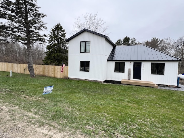 rear view of property featuring fence, a wooden deck, a yard, and metal roof