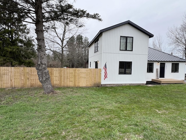 exterior space featuring a lawn, fence, and a deck