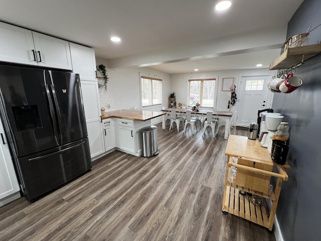 kitchen with a peninsula, black fridge, dark wood-style floors, and recessed lighting
