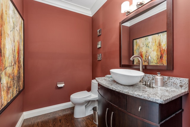 bathroom with wood finished floors, toilet, vanity, baseboards, and crown molding