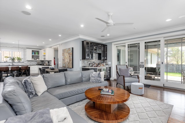 living area with recessed lighting, ceiling fan, crown molding, bar, and french doors