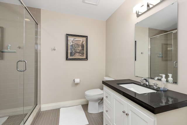 bathroom with toilet, a stall shower, vanity, and baseboards