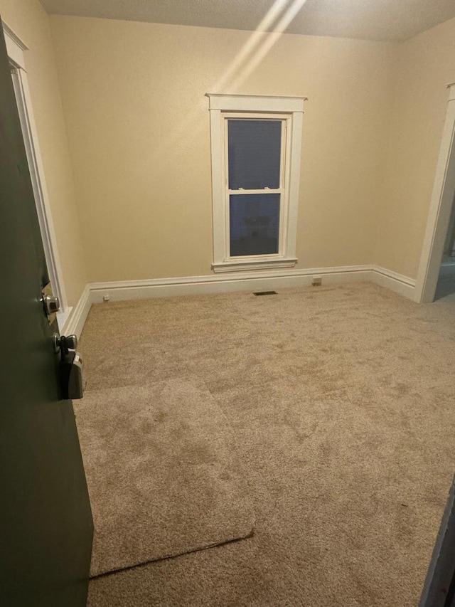 carpeted empty room with visible vents and baseboards