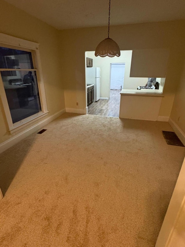 unfurnished dining area featuring visible vents, baseboards, and light colored carpet