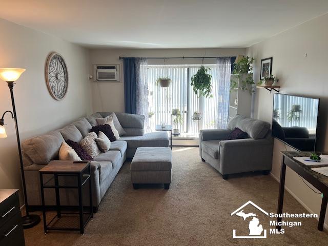 carpeted living area with a baseboard heating unit and a wall mounted AC