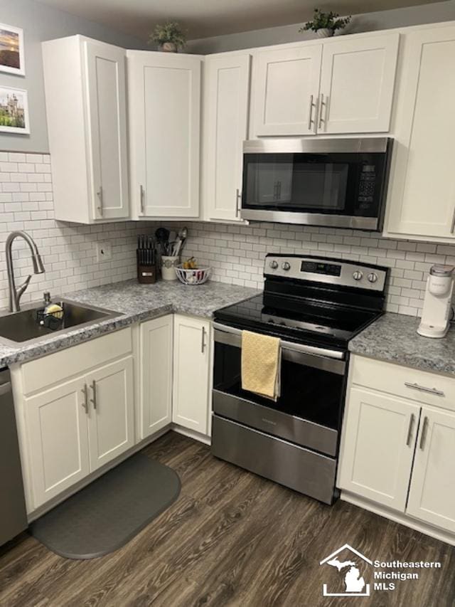 kitchen featuring white cabinets, a sink, appliances with stainless steel finishes, and dark wood finished floors