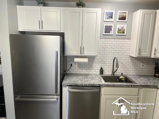 kitchen featuring white cabinets, a sink, backsplash, and appliances with stainless steel finishes