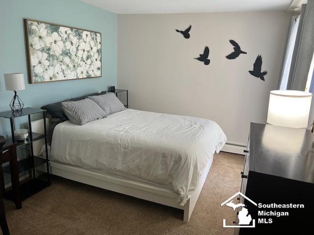 bedroom with a baseboard heating unit and carpet floors