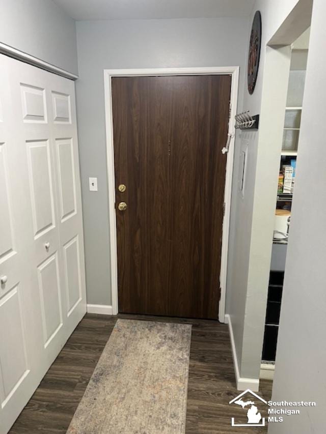 doorway featuring baseboards and dark wood-type flooring