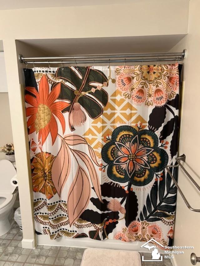 interior details featuring baseboards, a shower with curtain, and toilet