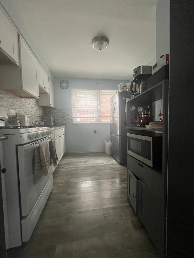 kitchen with white cabinets, wood finished floors, backsplash, and appliances with stainless steel finishes