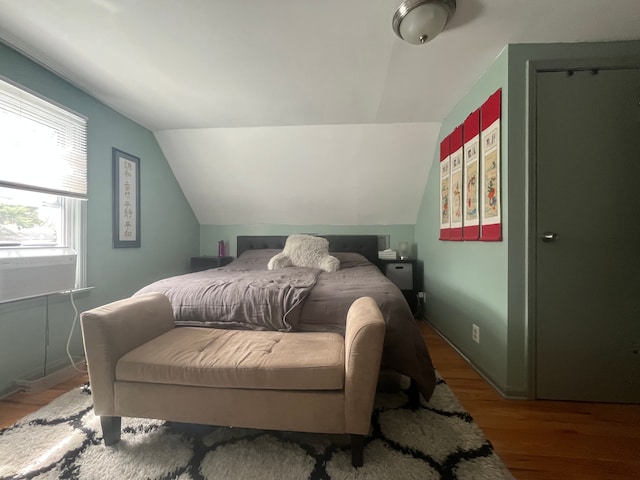 bedroom with vaulted ceiling and wood finished floors