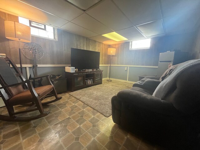 living room with wooden walls, a healthy amount of sunlight, and a drop ceiling