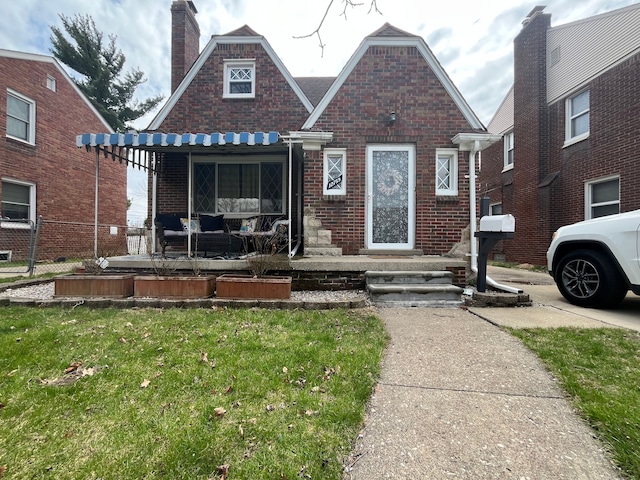 view of front of home featuring a chimney, brick siding, and a front yard