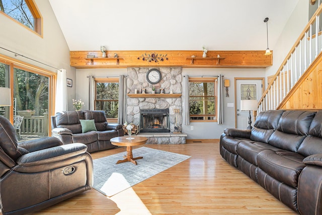 living area with wood finished floors, high vaulted ceiling, and stairs