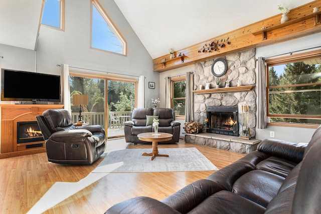 living area featuring a fireplace, a healthy amount of sunlight, and high vaulted ceiling