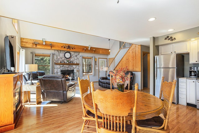 dining area with light wood-type flooring, a fireplace, stairs, and recessed lighting