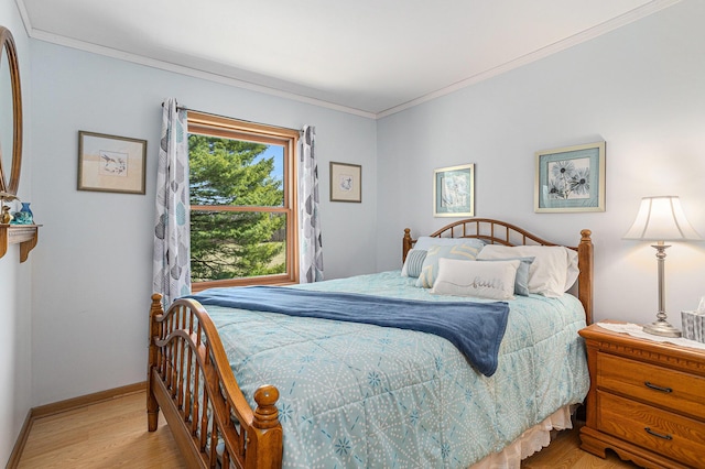 bedroom with crown molding, light wood finished floors, and baseboards