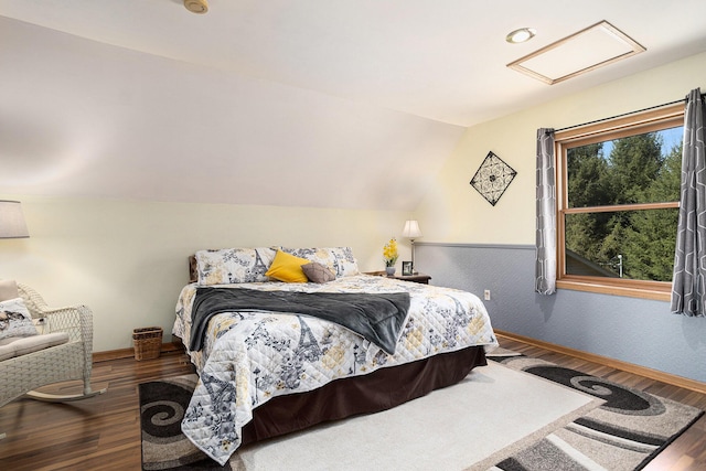 bedroom with lofted ceiling, baseboards, wood finished floors, and attic access