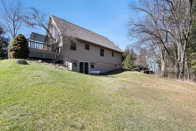 rear view of house featuring a lawn, roof with shingles, a deck, and a garage
