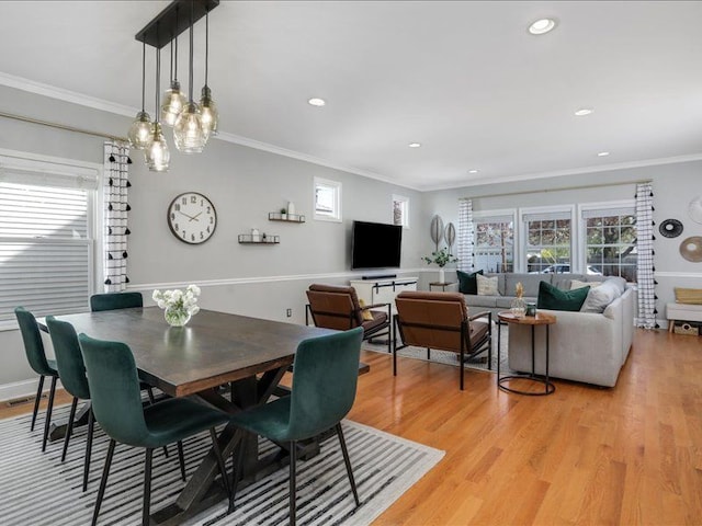 dining room with crown molding, a healthy amount of sunlight, and light wood finished floors
