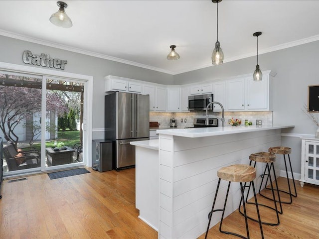 kitchen with light countertops, appliances with stainless steel finishes, decorative backsplash, and a peninsula