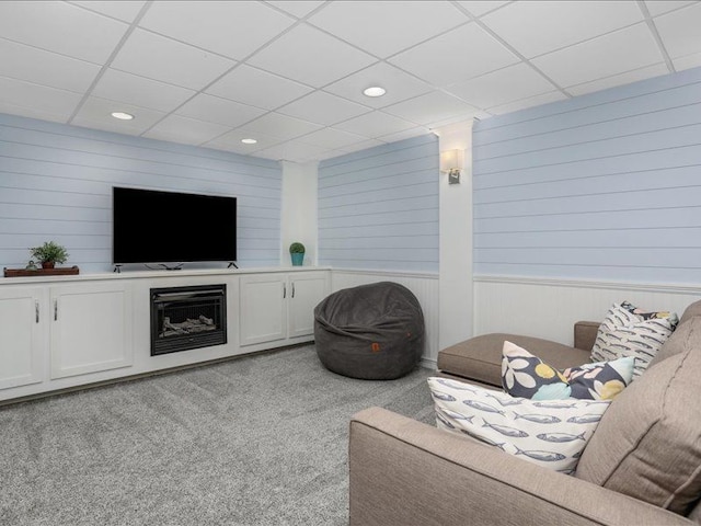 living room with wood walls, a drop ceiling, recessed lighting, and light colored carpet