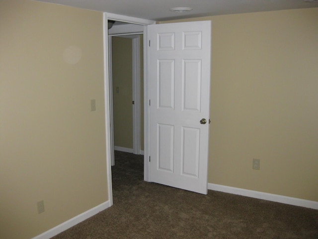 unfurnished room with dark carpet and baseboards