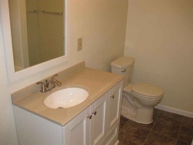 bathroom featuring toilet, vanity, and baseboards