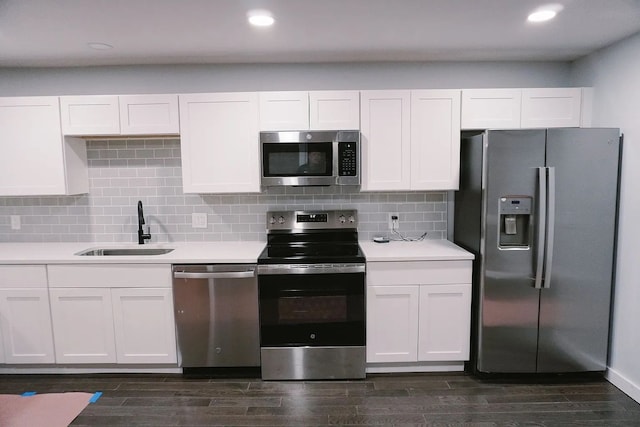 kitchen featuring dark wood-style floors, stainless steel appliances, light countertops, a sink, and white cabinetry