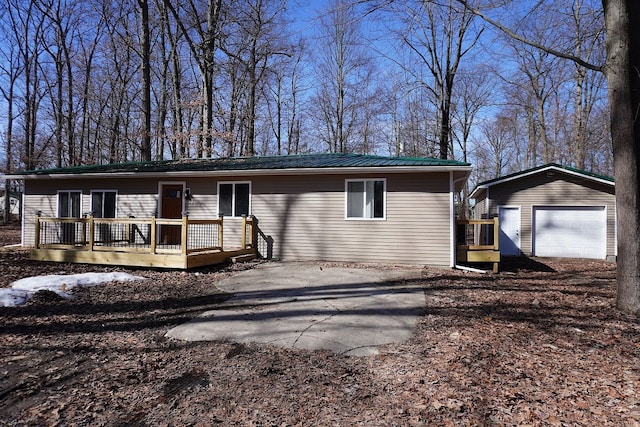 view of front facade with a wooden deck, metal roof, an outdoor structure, and a garage
