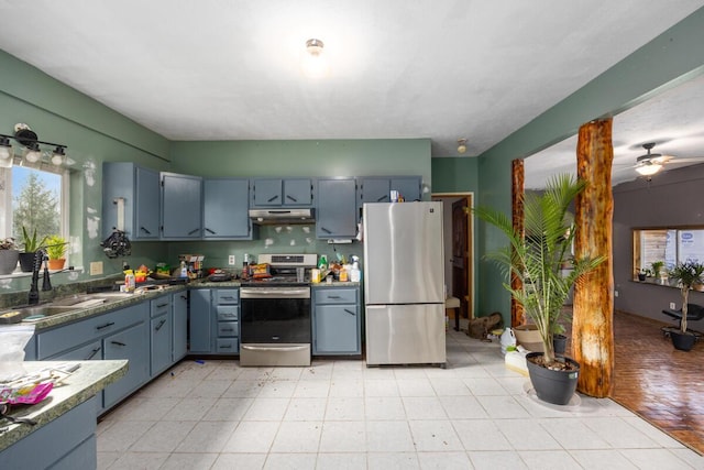 kitchen with under cabinet range hood, light floors, stainless steel appliances, a ceiling fan, and a sink