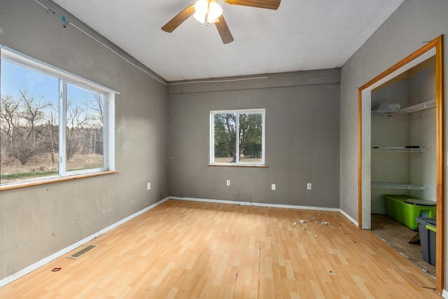 unfurnished bedroom featuring visible vents, baseboards, a ceiling fan, wood finished floors, and a closet