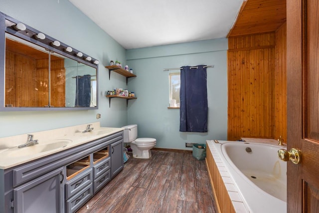 bathroom featuring tiled tub, a sink, double vanity, and toilet