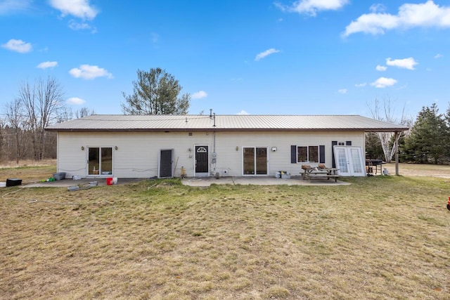 rear view of house with a patio area, french doors, a lawn, and metal roof