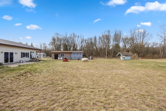view of yard featuring an outbuilding, a patio, and a storage unit